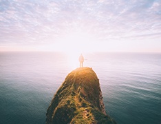 Person standing on mountain above the sea