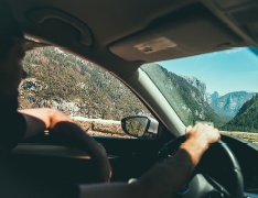 hand on steering wheel, mountains behind