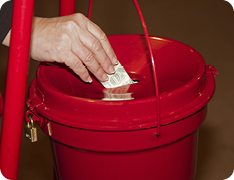 hand depositing donation into red Salvation Army bucket