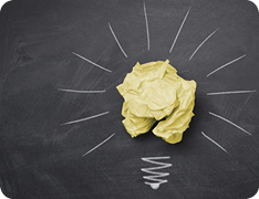 a crumpled up piece of paper surrounded by chalk drawings to make it look like a lightbulb