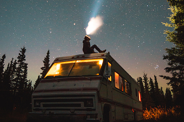person sitting on van roof under night sky