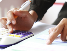 hands working with pen, calculator, and printed spreadsheets