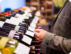 Consumer standing at long wine rack