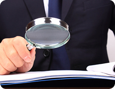 Businessman holding magnifying glass over textbook